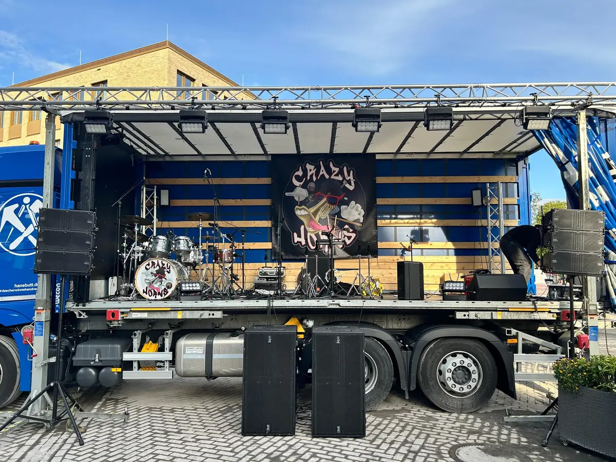 Bühne auf einem Lkw-Auflieger mit Schlagzeug, Banner der Band Crazy Horns, Lautsprechern und Scheinwerfern